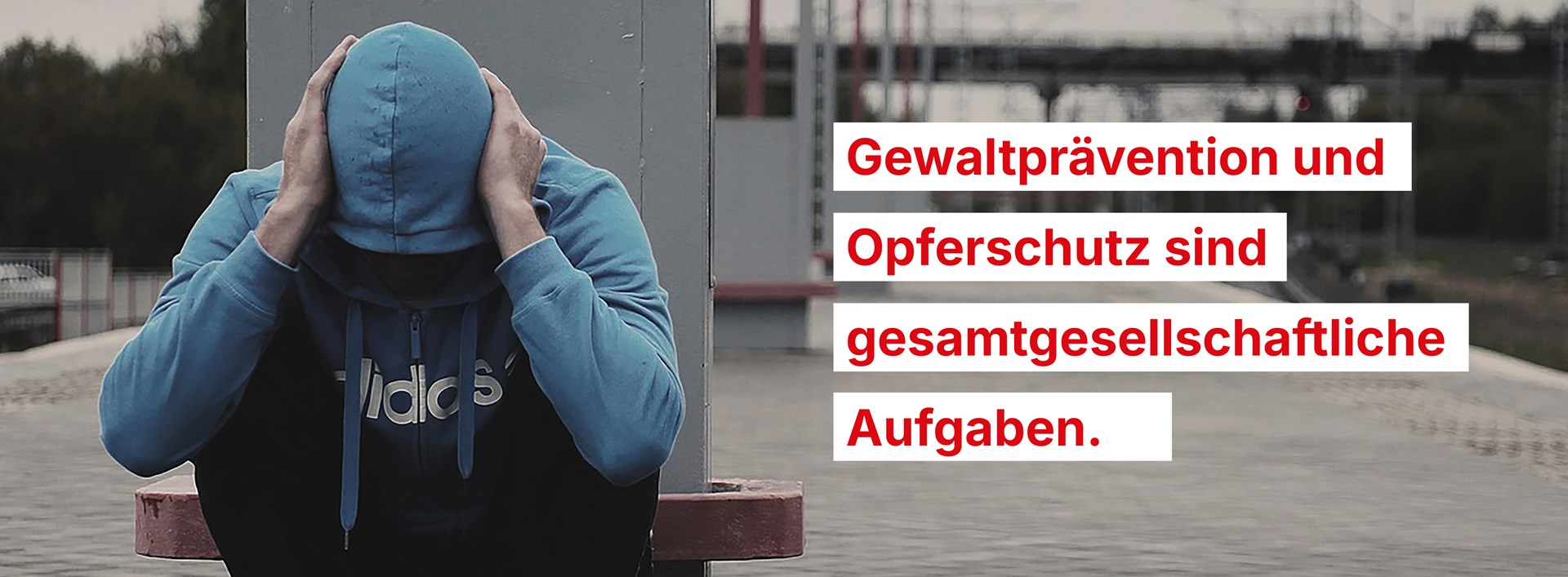 Mann kauert am Bahnsteig. Daneben steht: Gewaltprävention und Opferschutz sind gesamtgesellschaftliche Aufgaben